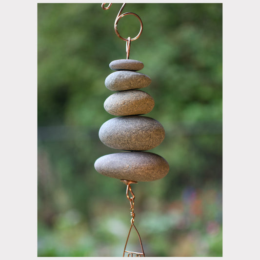 Decorative hanging with stacked stones against a blurred natural background