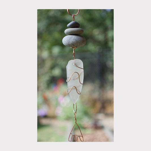 Decorative hanging with stones and wire art against a blurred natural background