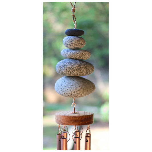 Stacked stone wind chime with copper accents against a blurred natural background