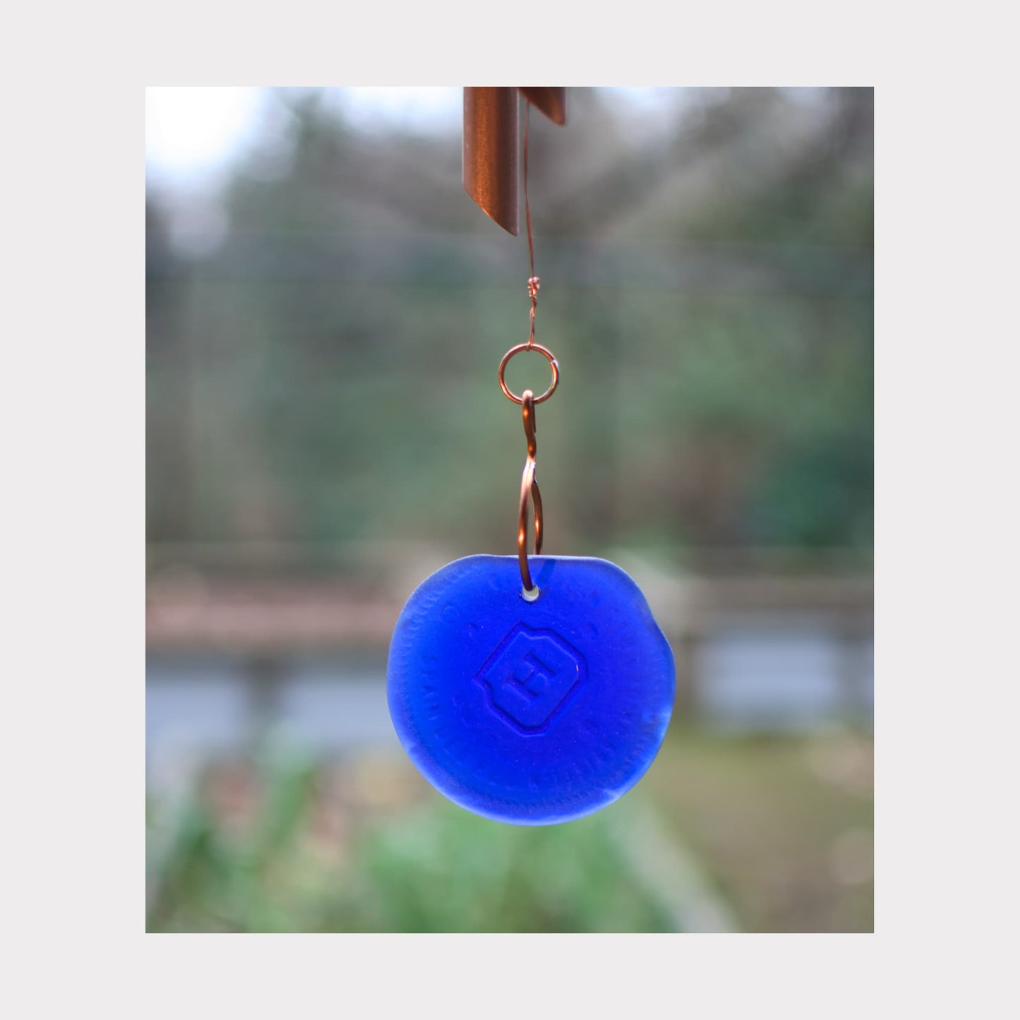 Detail of the cobalt blue glass windsail on a handmade copper wind chime.