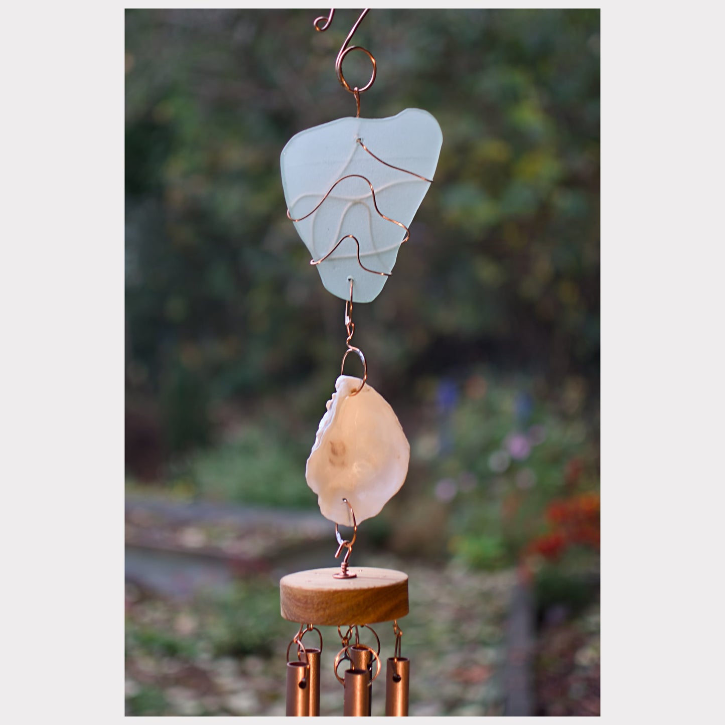 Decorative wind chime with natural elements against a blurred natural background