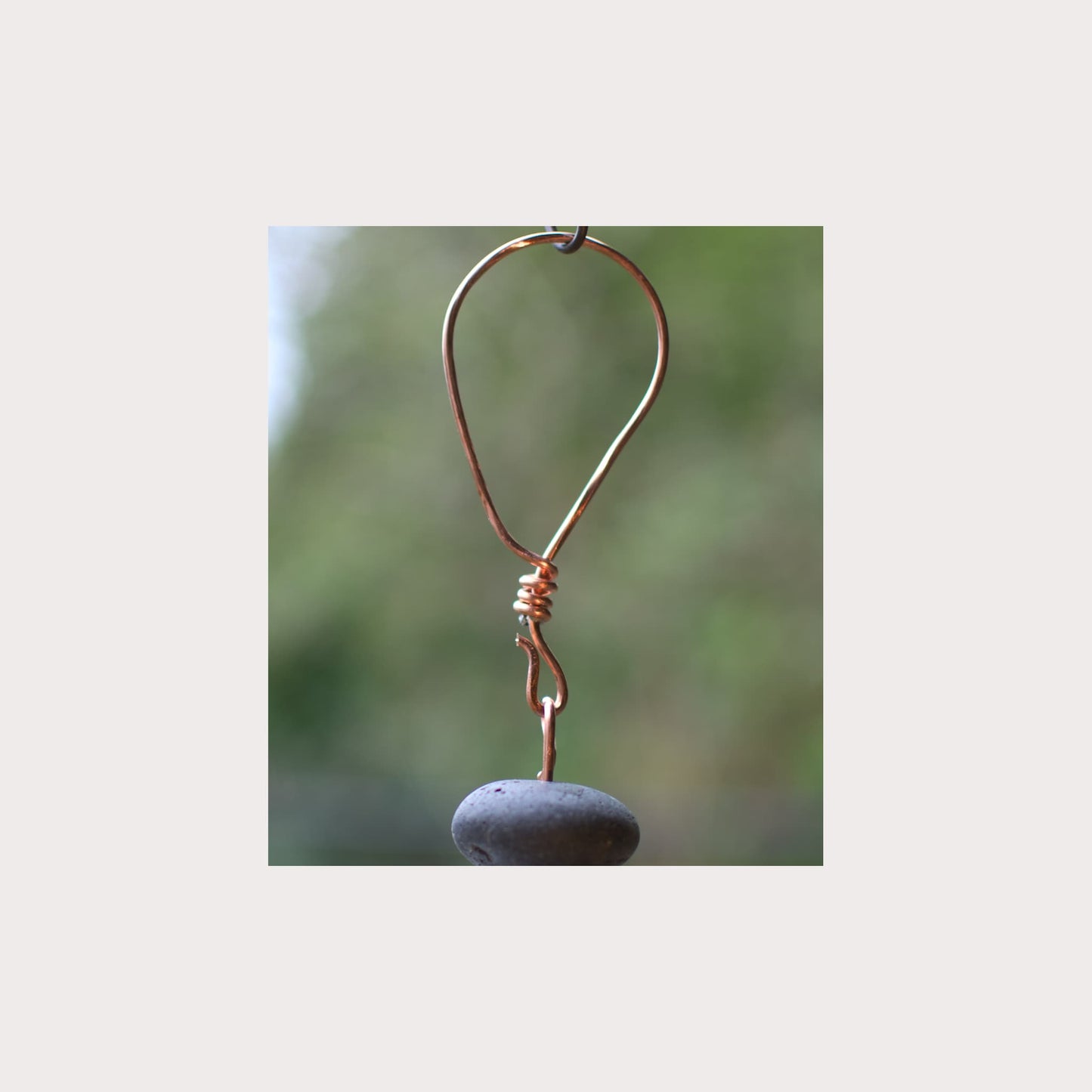 Copper hook with a stone on a blurred natural background