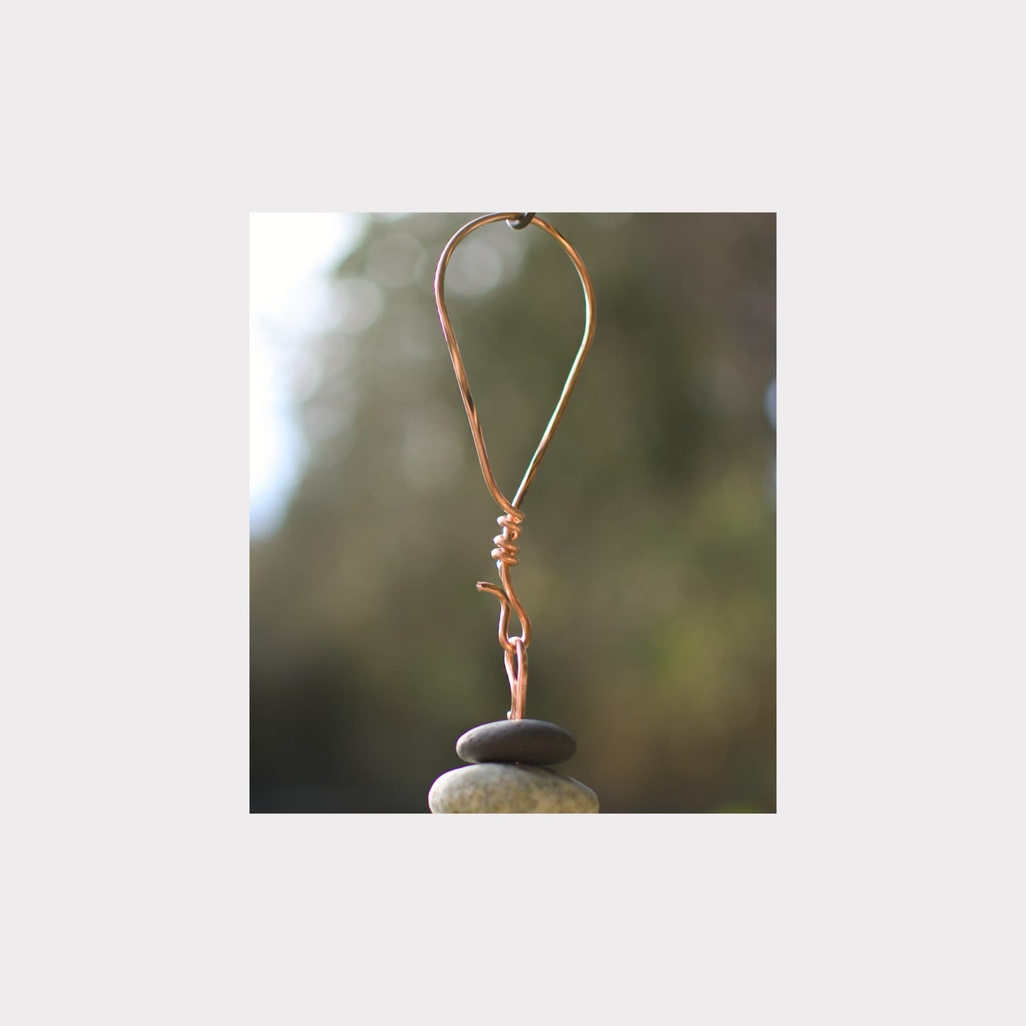 Copper wire hook on a stone with a blurred natural background
