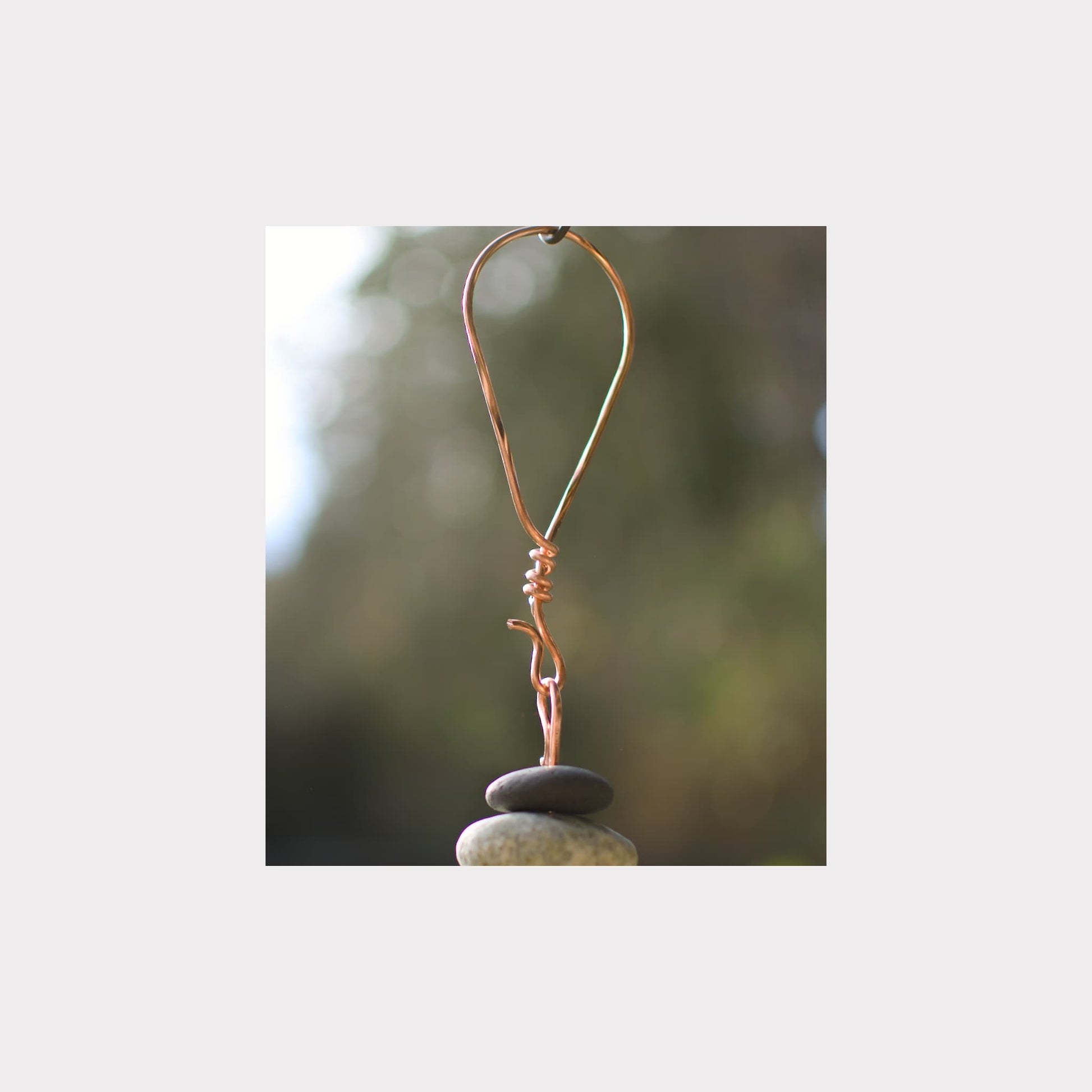 Copper wire hook on a stone with a blurred natural background