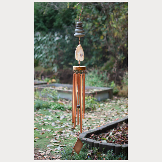 Decorative wind chime with stones and an oyster half shell  in a garden setting