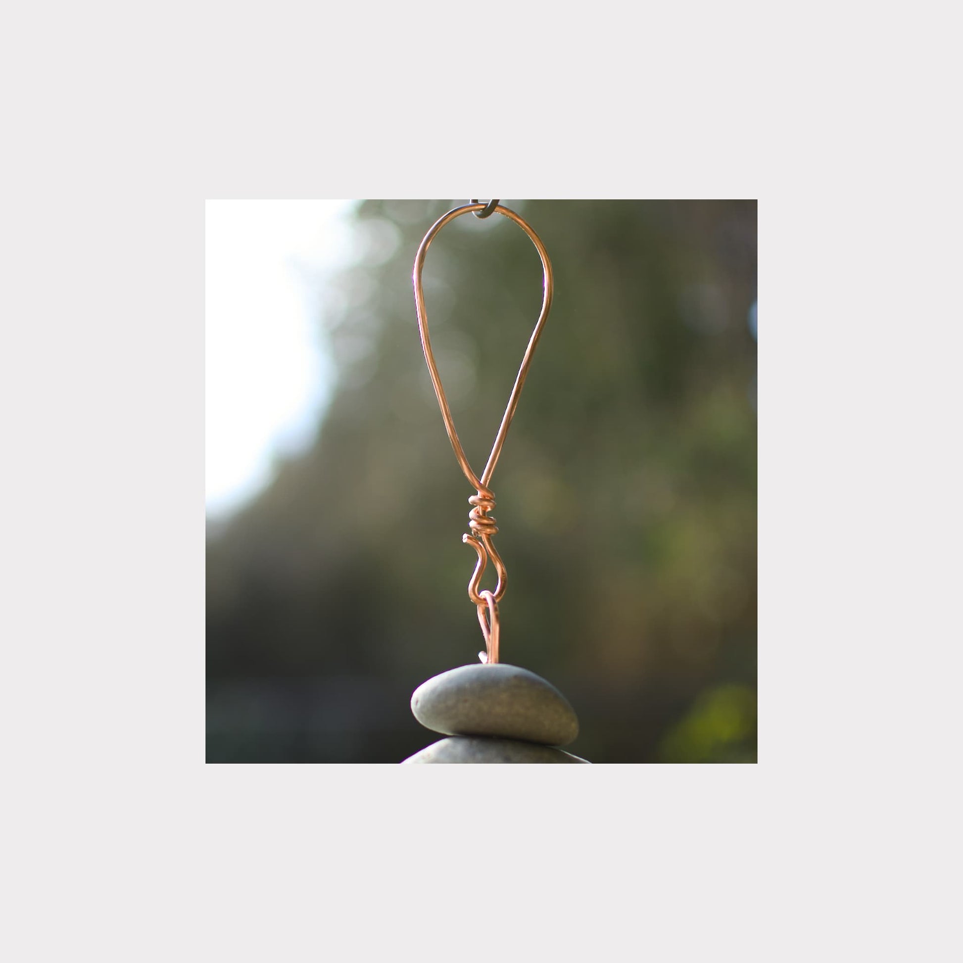 Copper wire hook on a stone with a blurred natural background
