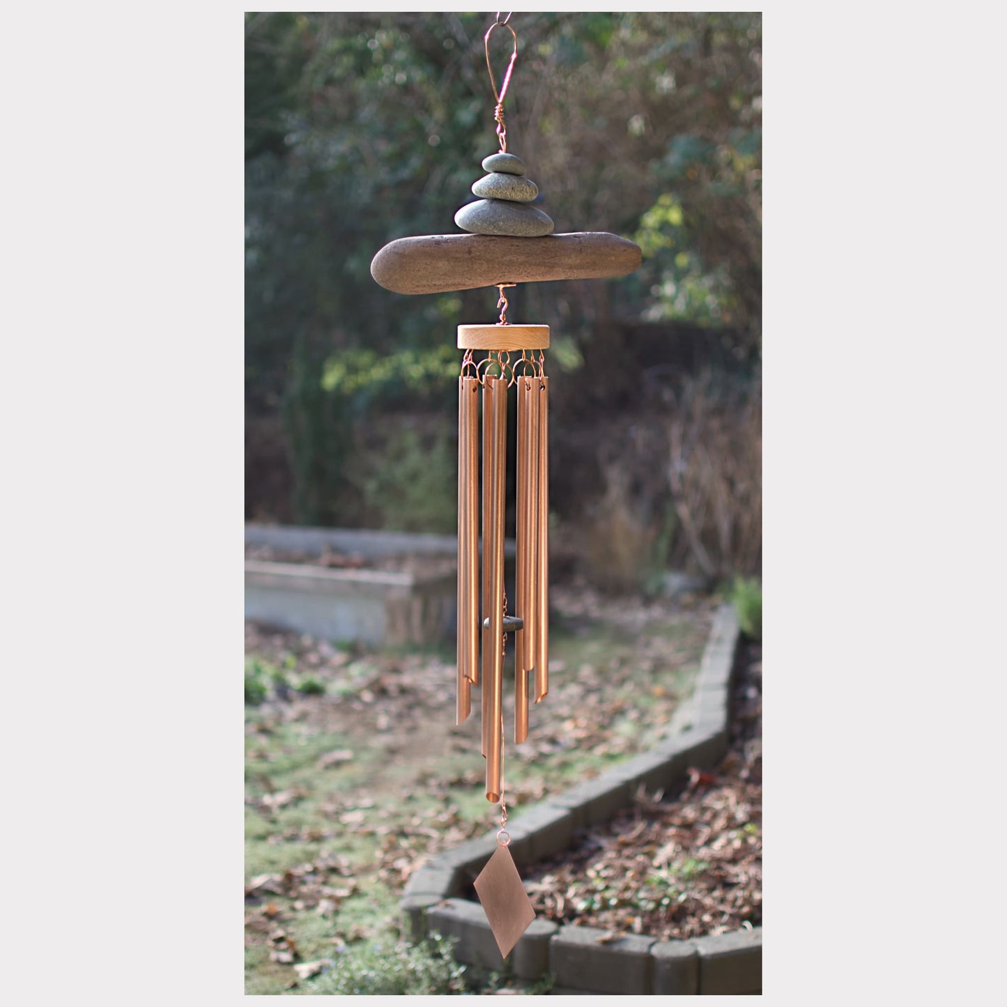 Decorative wind chime with stones on a blurred garden background