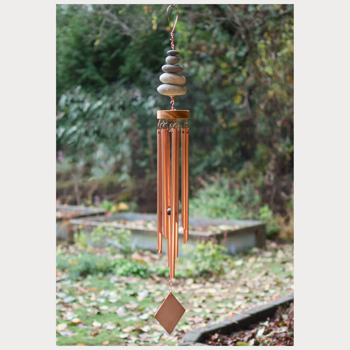 Copper wind chime with stones against a natural background