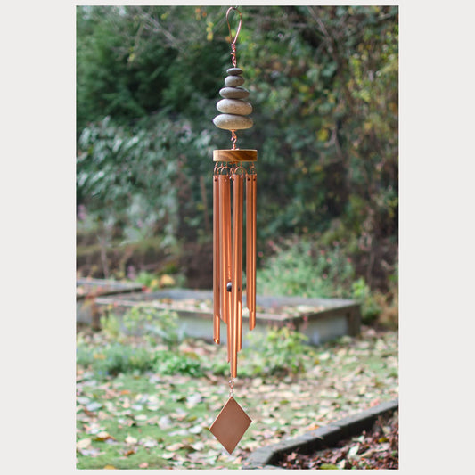 Copper wind chime with stones against a natural background