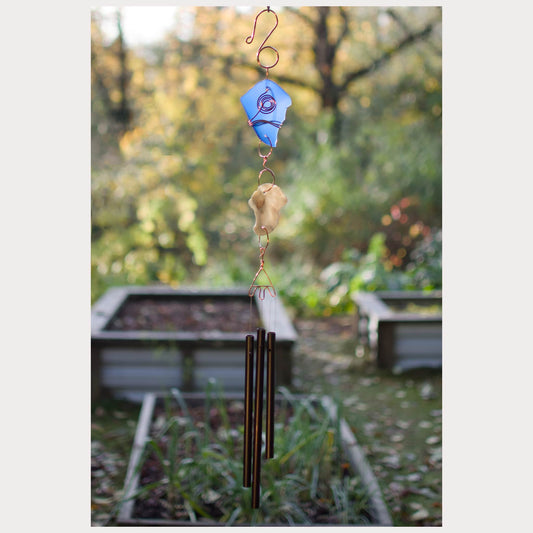 Decorative wind chime with colorful stones against a garden background