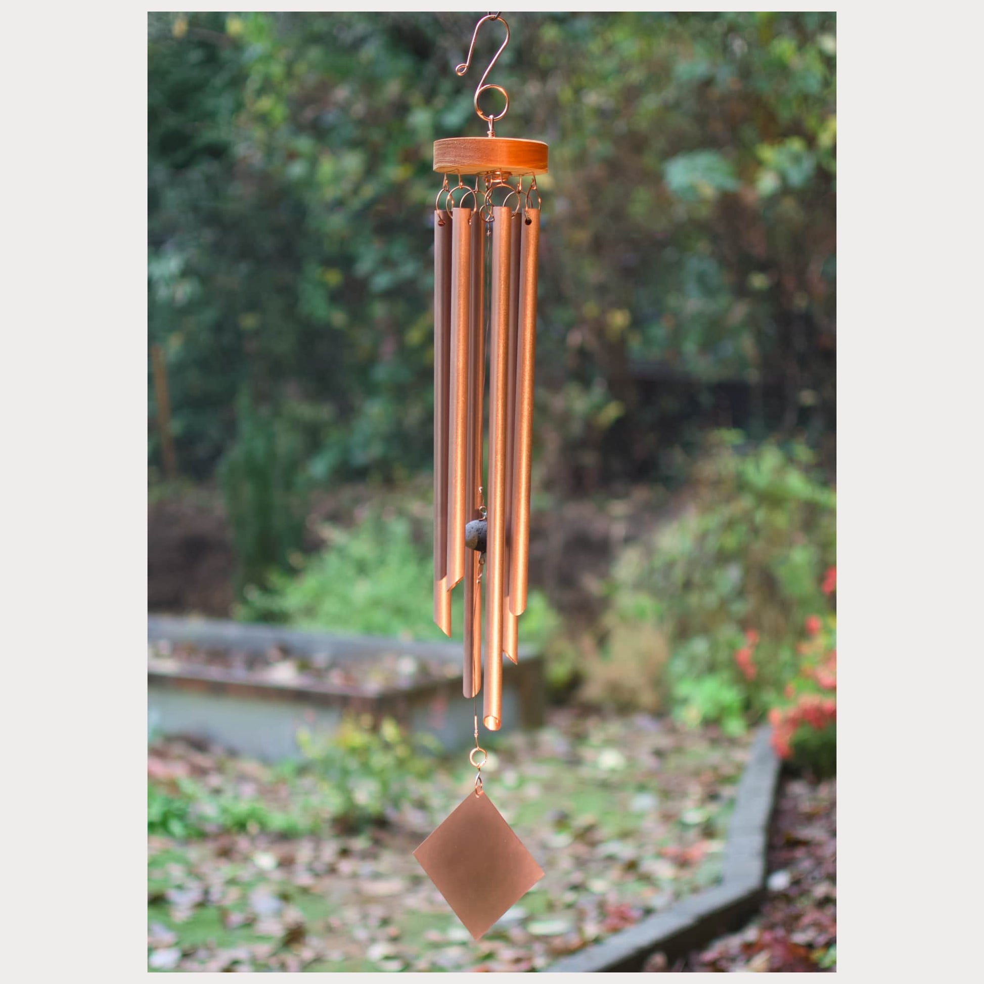 Copper wind chime with a blurred garden background